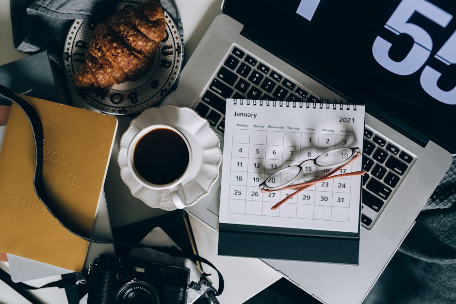 A serene workspace setup with coffee, croissant, laptop, and calendar, ideal for organizing plans.