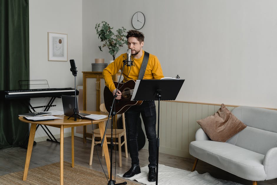 A man plays guitar and sings in a cozy home music studio, creating music.