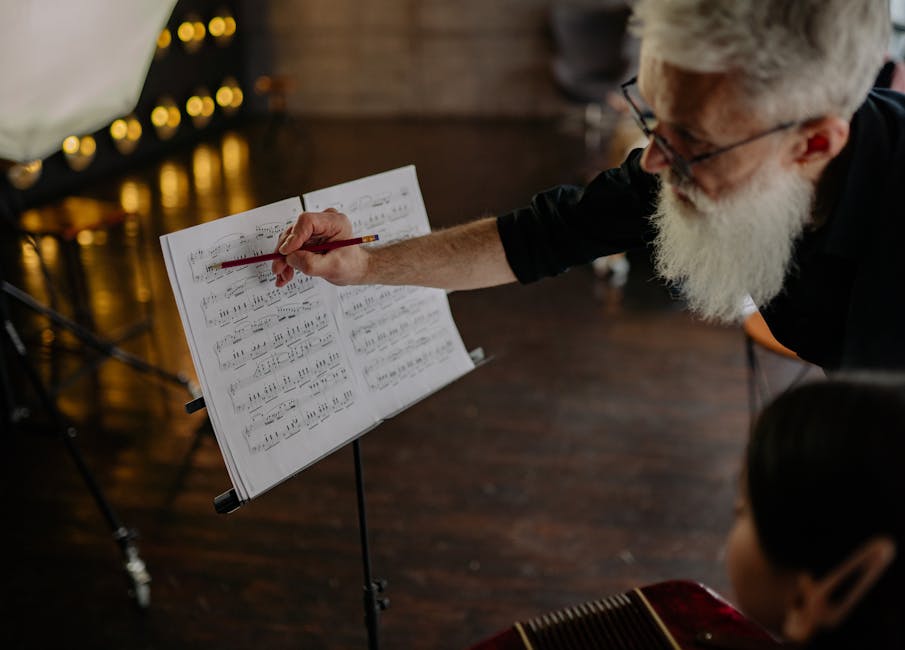An elderly music teacher guides a student with sheet music and pencil indoors.